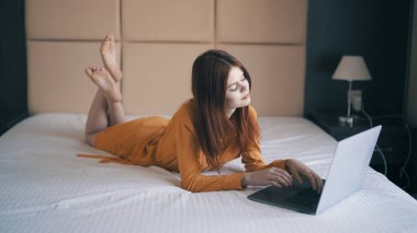 Kadın dizüstü bilgisayarın önünde yatarken çalışıyor.