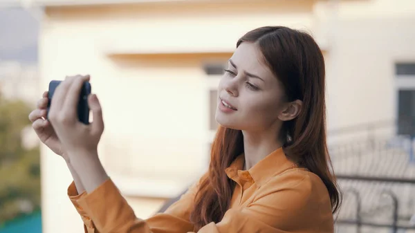 Cheerful woman in nature with phones in her hands shoots on camera — Stock Photo, Image