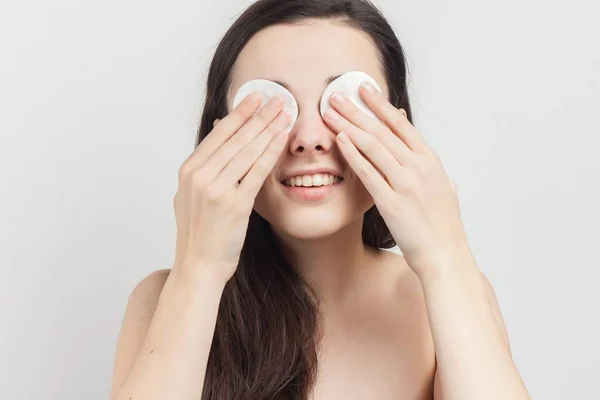 Mujer bonita con hombros desnudos limpia cosméticos piel limpia con una esponja — Foto de Stock