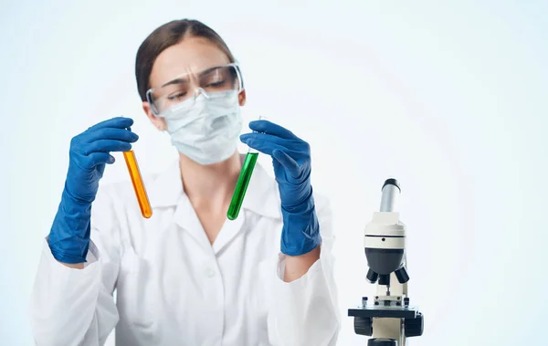 Жінка-біолог в медичних рукавичках вакцинація мікроскоп на дослідницькій таблиці в хімічному елементі — стокове фото