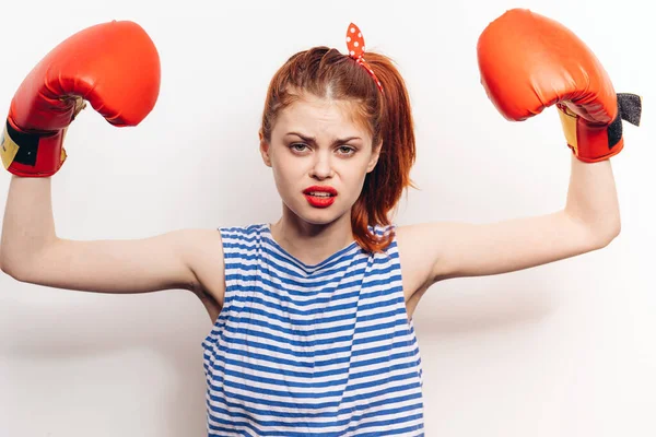 Mujer fuerte se dedican al boxeo con guantes rojos sobre un fondo claro emociones de agresión — Foto de Stock