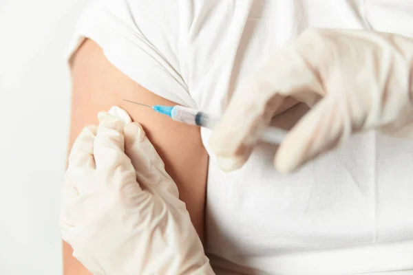 Een arts met handschoenen die injecteert in de schouder close-up covid vaccinatie — Stockfoto