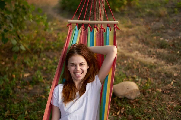 Mulher feliz encontra-se em uma rede ao ar livre na floresta rindo — Fotografia de Stock