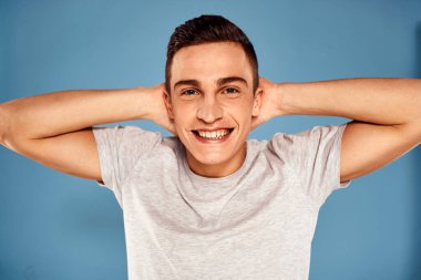 Beyaz tişörtlü sevimli adam elleri mavi arka planda.