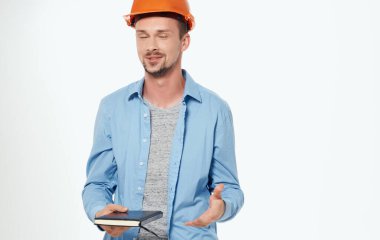 Turuncu şapkalı erkek mimar gri arka planda çalışıyor.