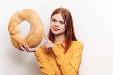 Parlak makyajlı mutlu bir kadın hafif bir arka planda elinde bir somun ekmek tutuyor.