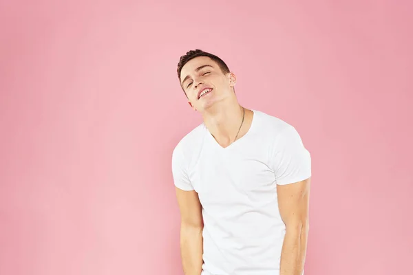 Alegre hombre guapo en blanco camiseta emociones rosa aislado fondo — Foto de Stock