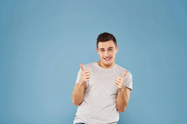 Glad man i en vit t-shirt gester med händerna känslor blå bakgrund — Stockfoto