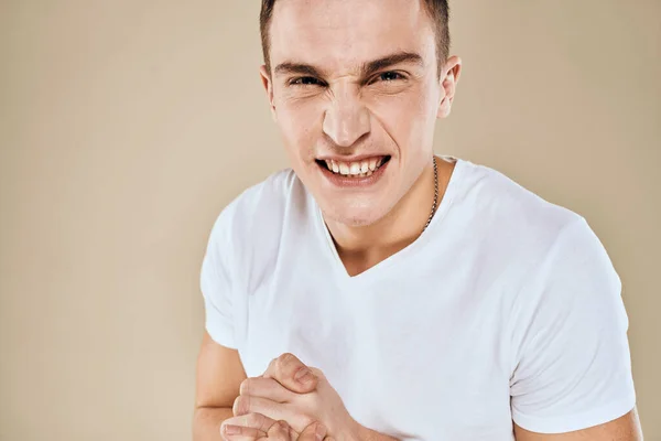 Homme avec expression faciale mécontente émotions blanc t-shirt gestes avec les mains fond beige — Photo