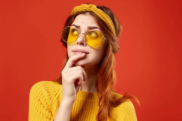 Mulher emocional usando óculos camisola amarela roupas casuais hippie estúdio fundo vermelho — Fotografia de Stock