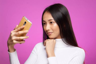 Elinde telefon teknolojisi olan sevimli Asyalı kadın pembe arka plan