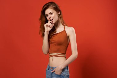 Kırmızı tişörtlü ve kot pantolonlu neşeli güzel bir kadın. Göz alıcı moda hipster 'ı.