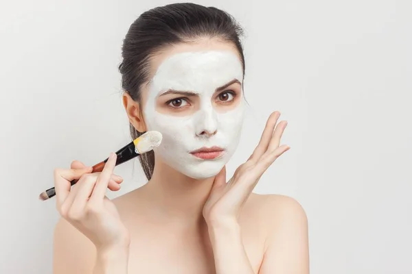 Morena atraente aplicando máscara no rosto com cuidado da pele escova — Fotografia de Stock
