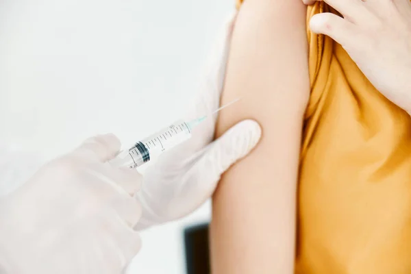 En läkare injicerar ett covid-19 vaccin i en kvinnlig skuldra — Stockfoto