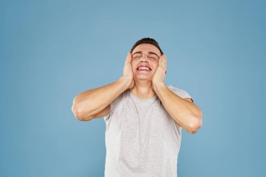 Beyaz tişörtlü neşeli bir adam elleri ve duyguları mavi arka planda hareket ediyor.