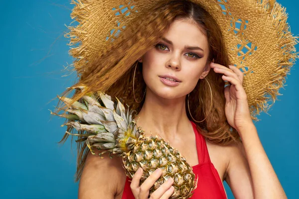 Mulher em um chapéu de palha com abacaxi em suas mãos cabelo ondulado frutas exóticas você verão azul fundo férias — Fotografia de Stock
