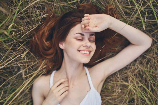 Mujer feliz se encuentra en el heno al aire libre en un vestido blanco y gestos con las manos —  Fotos de Stock