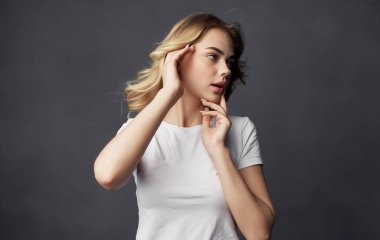 Güzel kadın beyaz tişört cazibesi koyu arkaplan pozu veriyor