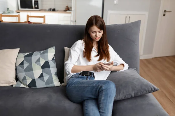 Mulher olhando para o telefone sentado no sofá apartamento de férias — Fotografia de Stock