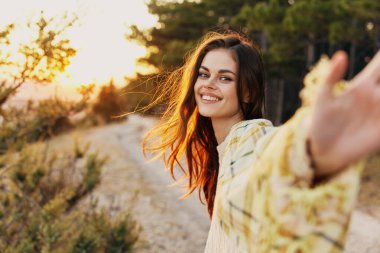 Doğadaki mutlu kadın avucunu gösterir ve gülümser.