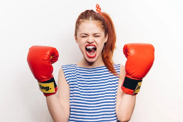 Femme aux cheveux roux en gants de boxe et un t-shirt rayé sur fond clair avec une bouche ouverte — Photo