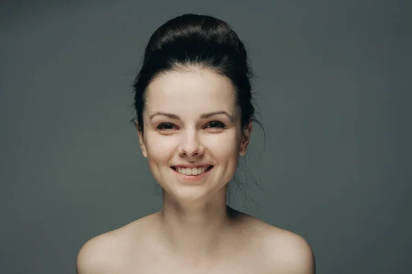 Όμορφη γυναίκα χαμογελώντας σε γκρι φόντο γυμνοί ώμοι περικοπή άποψη χτένισμα — Φωτογραφία Αρχείου