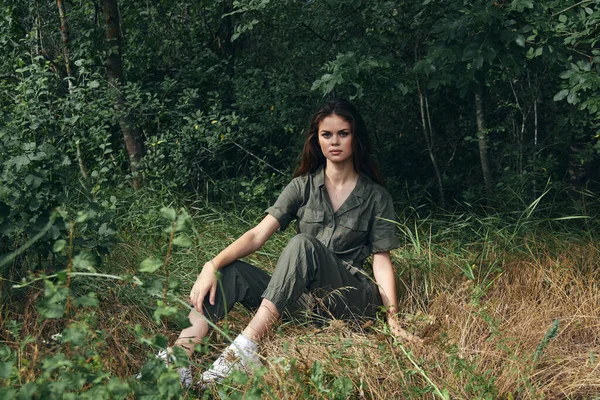 Mulher em macacão e tênis descansar na grama a floresta — Fotografia de Stock