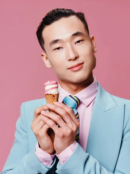 Aranyos férfi ázsiai megjelenés kék öltöny fagylalt életmód közelkép rózsaszín háttér élvezet — Stock Fotó