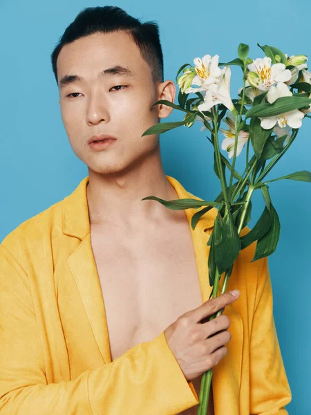 Homem de aparência asiática com buquê de flores brancas e feriados presentes fundo azul — Fotografia de Stock