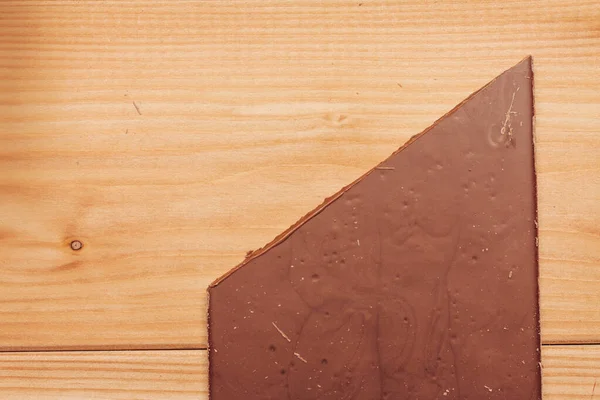 Barra de chocolate marrom cortada diagonalmente no fundo de madeira — Fotografia de Stock