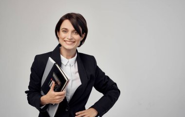 Elinde belgelerle siyah ceketli finans modeli bir kadın.