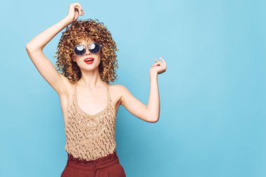 Güzel kadın kıvırcık saçlı, koyu renk güneş gözlüklü stüdyo kıyafetleri. 