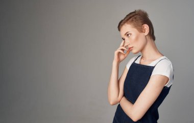 Kısa saçlı, yüzünde gri bir arka plan olan bir kadın.