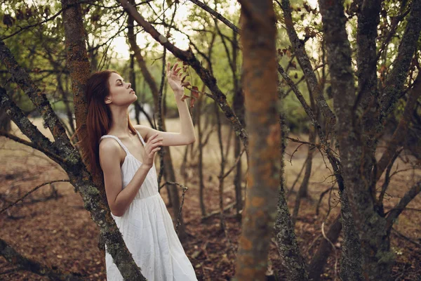 Bahçedeki ağaçların yanında beyaz yaz elbisesi giyen seksi kadın. — Stok fotoğraf