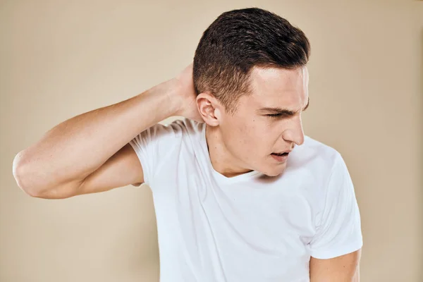 Man with displeased facial expression emotions white t-shirt gestures with hands beige background — Stock Photo, Image