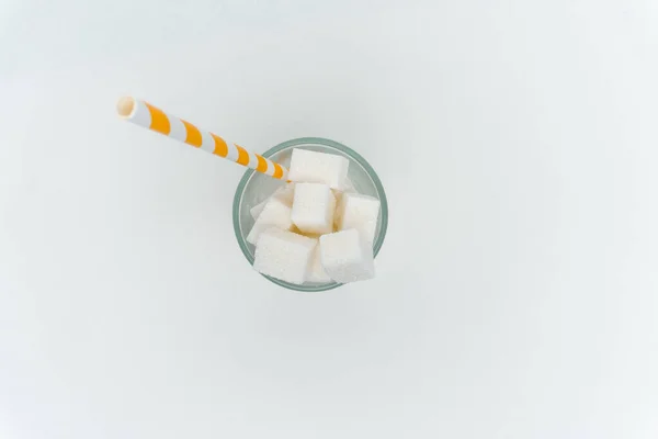 Terrones de azúcar en un vaso con un tubo dulce alto en calorías — Foto de Stock