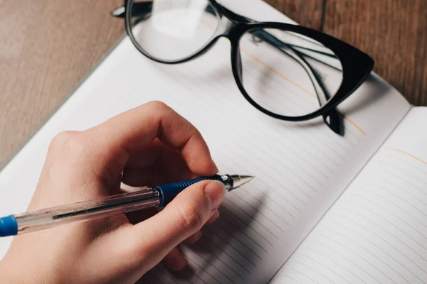 Блокнот, що пише окуляри на ручці стола — стокове фото