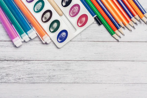 Lápices de colores acuarela pinturas y rotuladores plumas en la educación de la escuela de mesa de madera — Foto de Stock