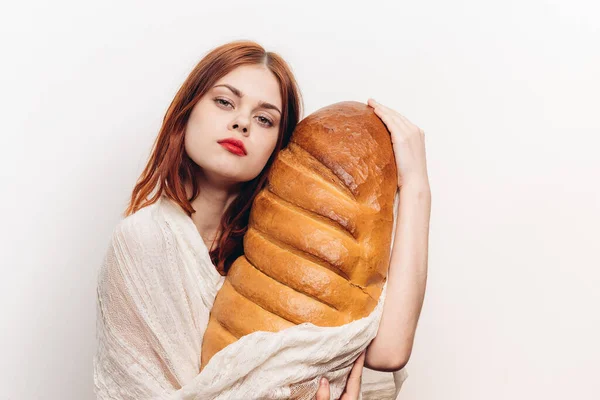 Mulher com maquiagem brilhante abraçando um grande pão em suas mãos — Fotografia de Stock