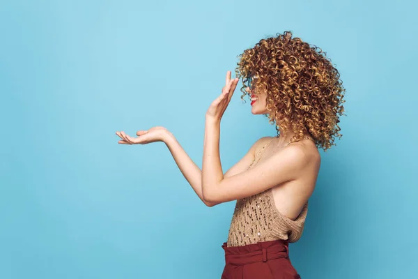 Mooie vrouw krullend haar zijaanzicht hand gebaren blauwe achtergrond studio kopiëren ruimte — Stockfoto