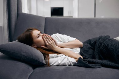 Kanepede uzanan kadın ellerini yüzüne koydu ve kendini kötü hissetti.