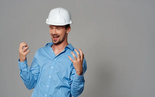 Architekt mit weißem Helm und blauem Hemd vor grauem Hintergrund — Stockfoto