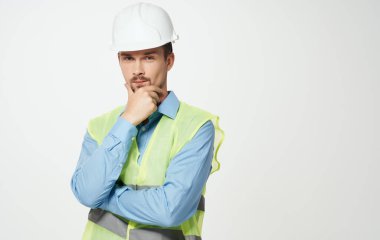 Beyaz kasklı ve yeşil yansıtıcı yelekli inşaat işçisi.