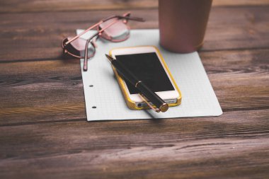 Ofis masası, not defteri gözlükleri, cep telefonu kahve fincanı.