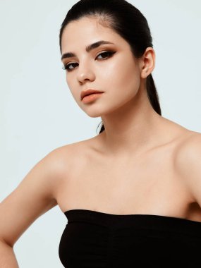 Çıplak omuzlu, gece makyajlı güzel bir kadın.