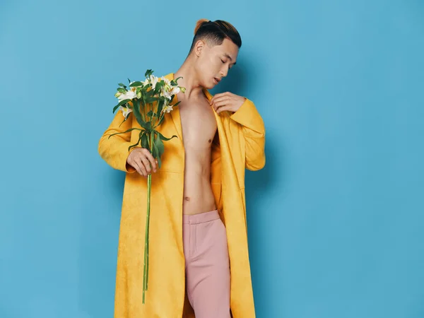 Homem romântico em um casaco amarelo com um buquê de flores perfumadas fundo azul vista cortada — Fotografia de Stock