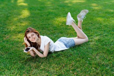 Neşeli kadın parkın bahçesinde uzanmış dinleniyor.