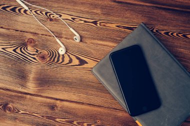 defter ahşap masa telefonu ve kulaklıklar.
