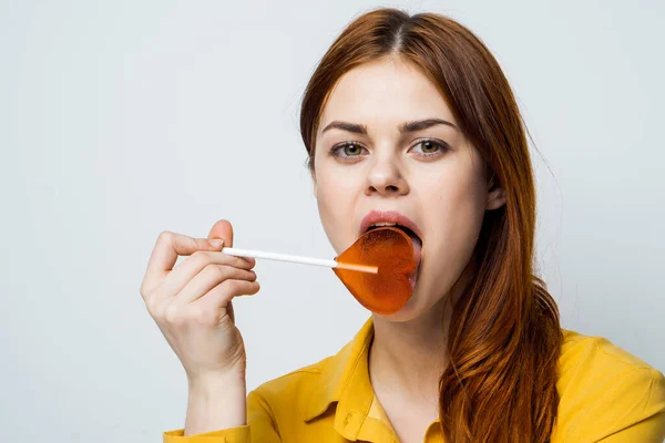 Atraente mulher segurando coração em forma de pirulito divertido estúdio — Fotografia de Stock