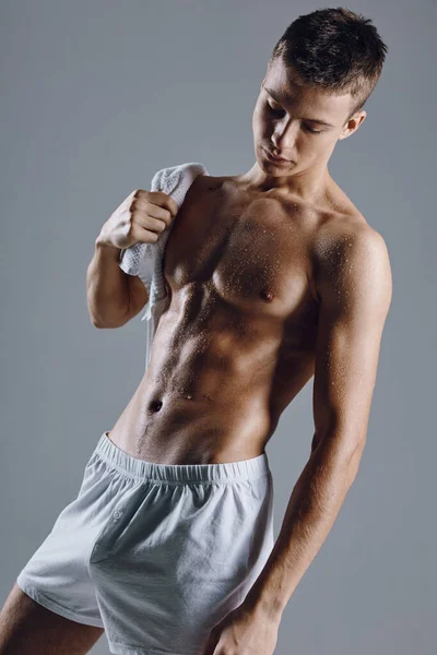 Athletic guy with a muscular body in white shorts with a towel on his shoulder Studio — Stock Photo, Image